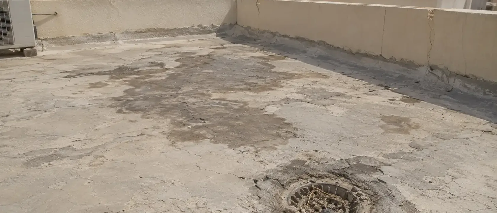 سطح خرساني بشروخ قديمة وبقع ماء حول فتحة التصريف يحتاج عزل أسطح بالرياض قبل المطر